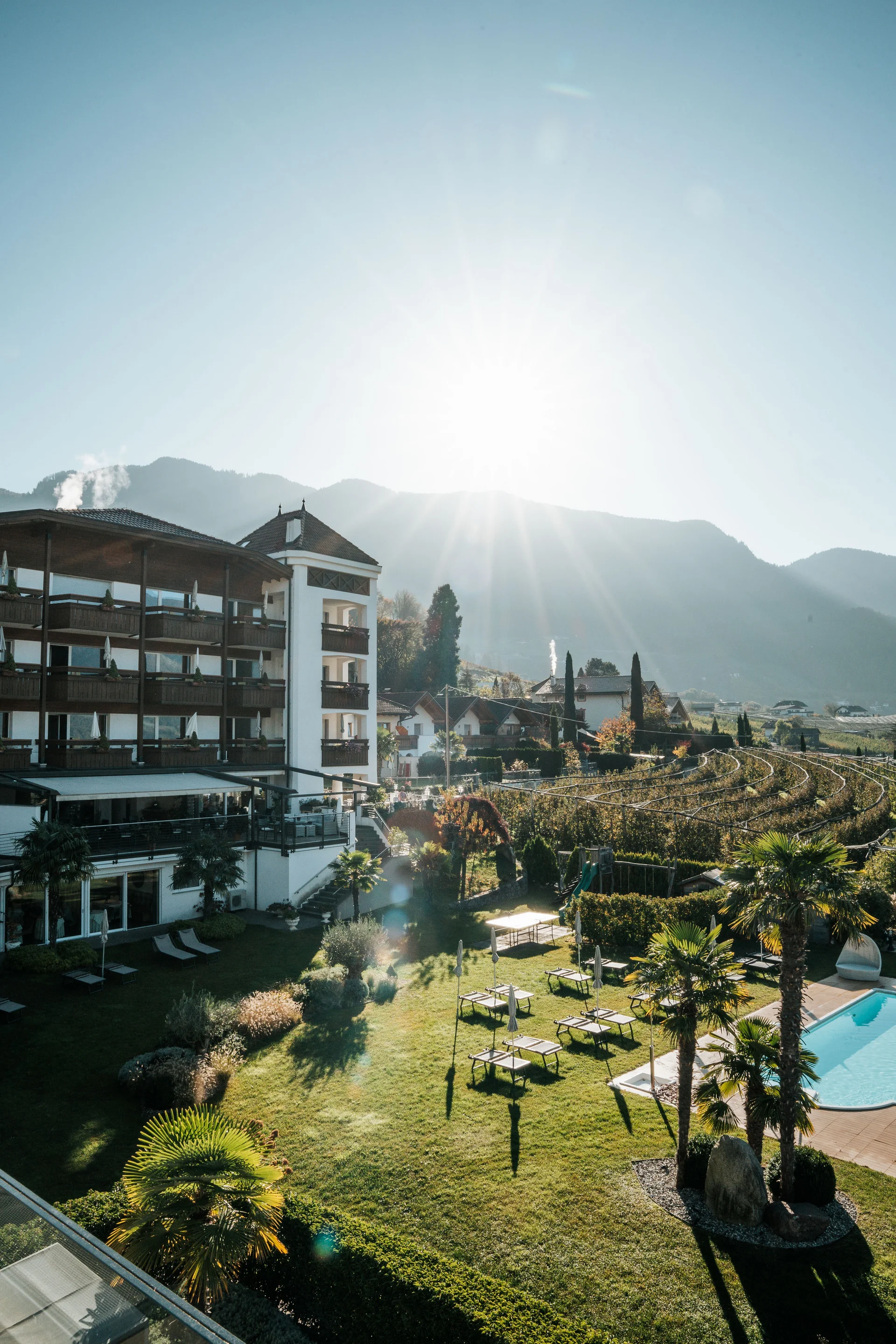 Euer Hotel in Schenna für Momente in #echtzeit Hotel mit Garten, Pool und bergiger Landschaft bei sonnigem Wetter