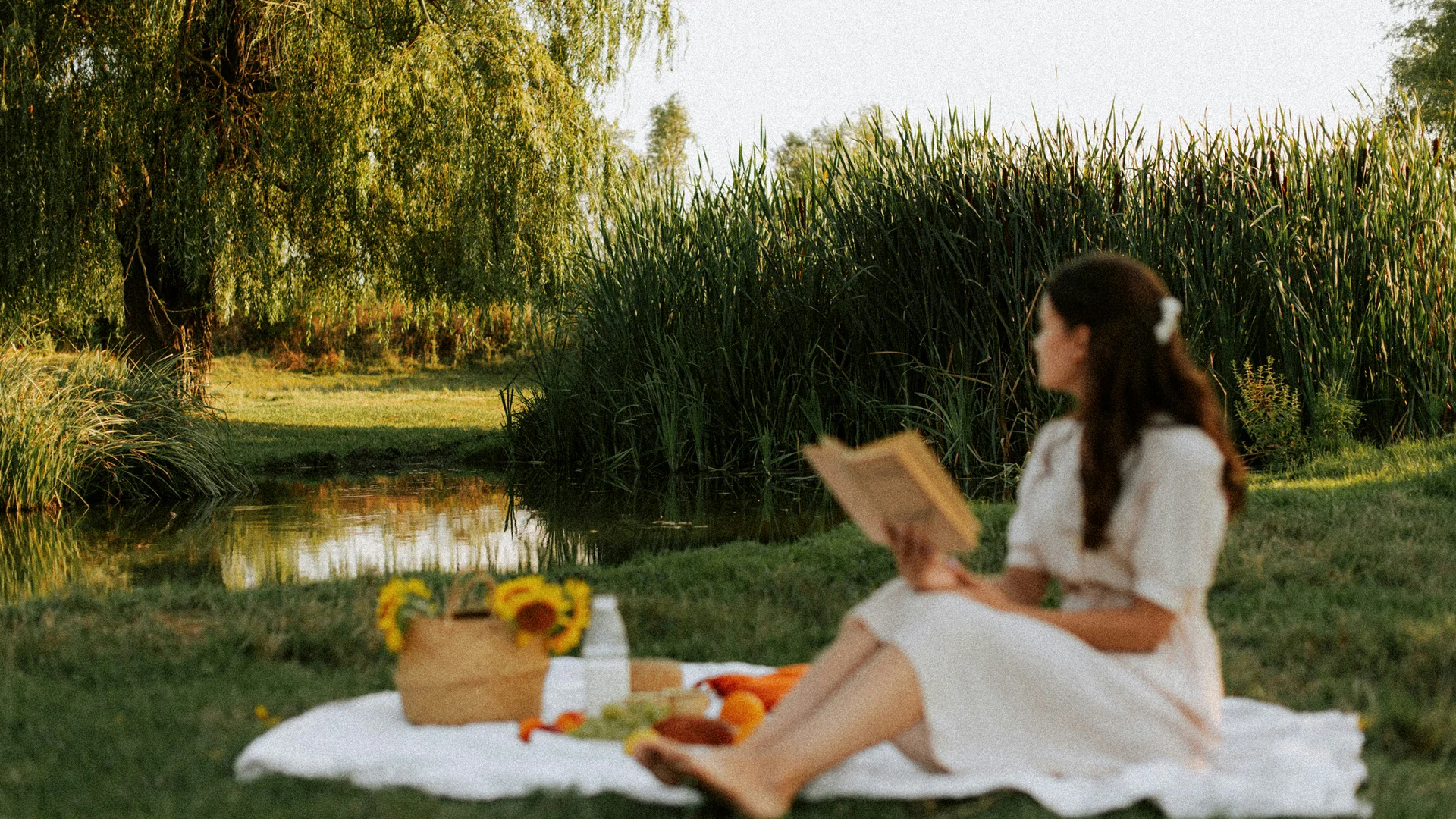 Euer Hotel in Schenna für Momente in #echtzeit Frau sitzt auf Picknickdecke am See und liest Buch im grünen Park
