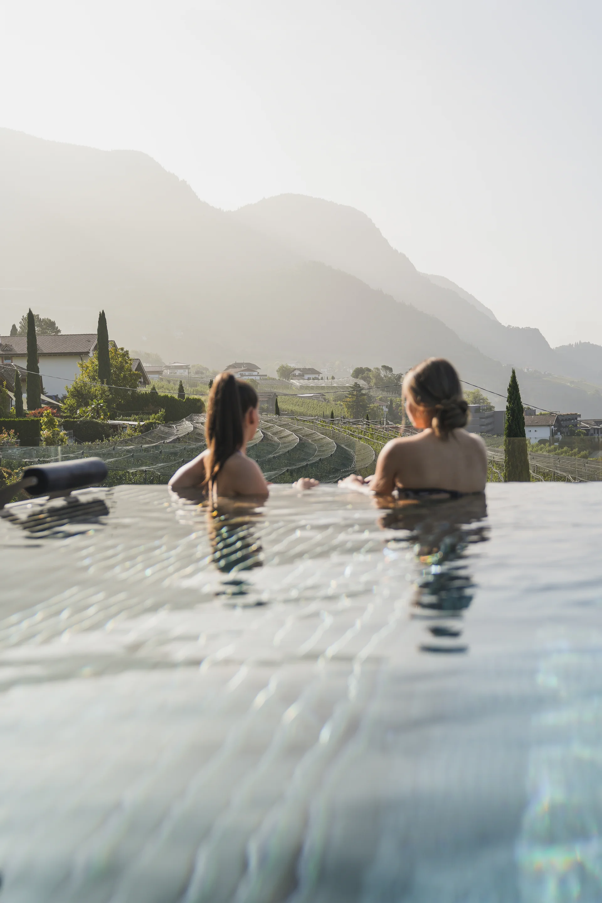Euer Hotel in Schenna für Momente in #echtzeit Zwei Frauen entspannen im Infinity-Pool mit Bergblick