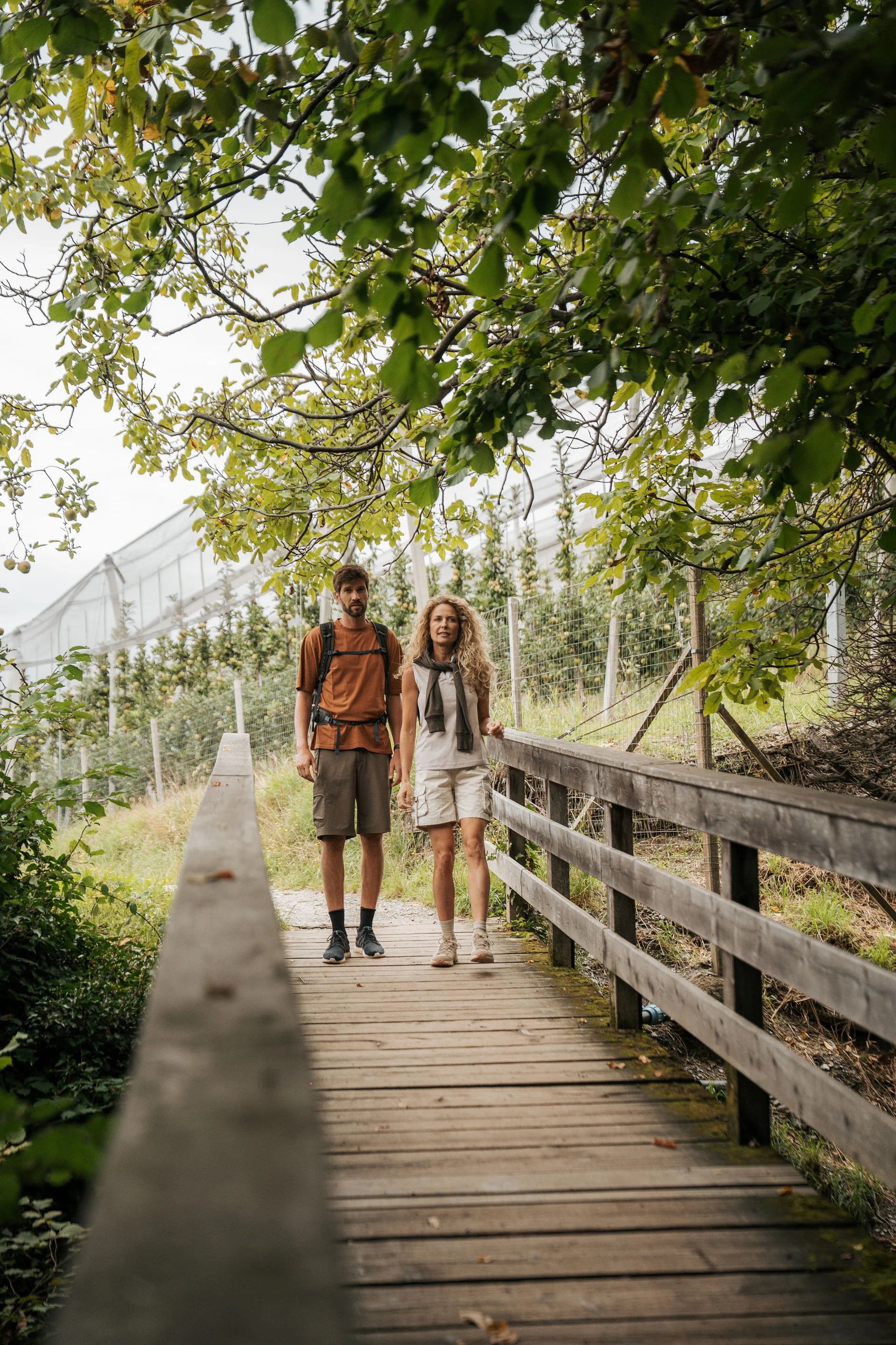 Euer Hotel in Schenna für Momente in #echtzeit Paar beim Spaziergang auf einem Holzsteg im grünen Park