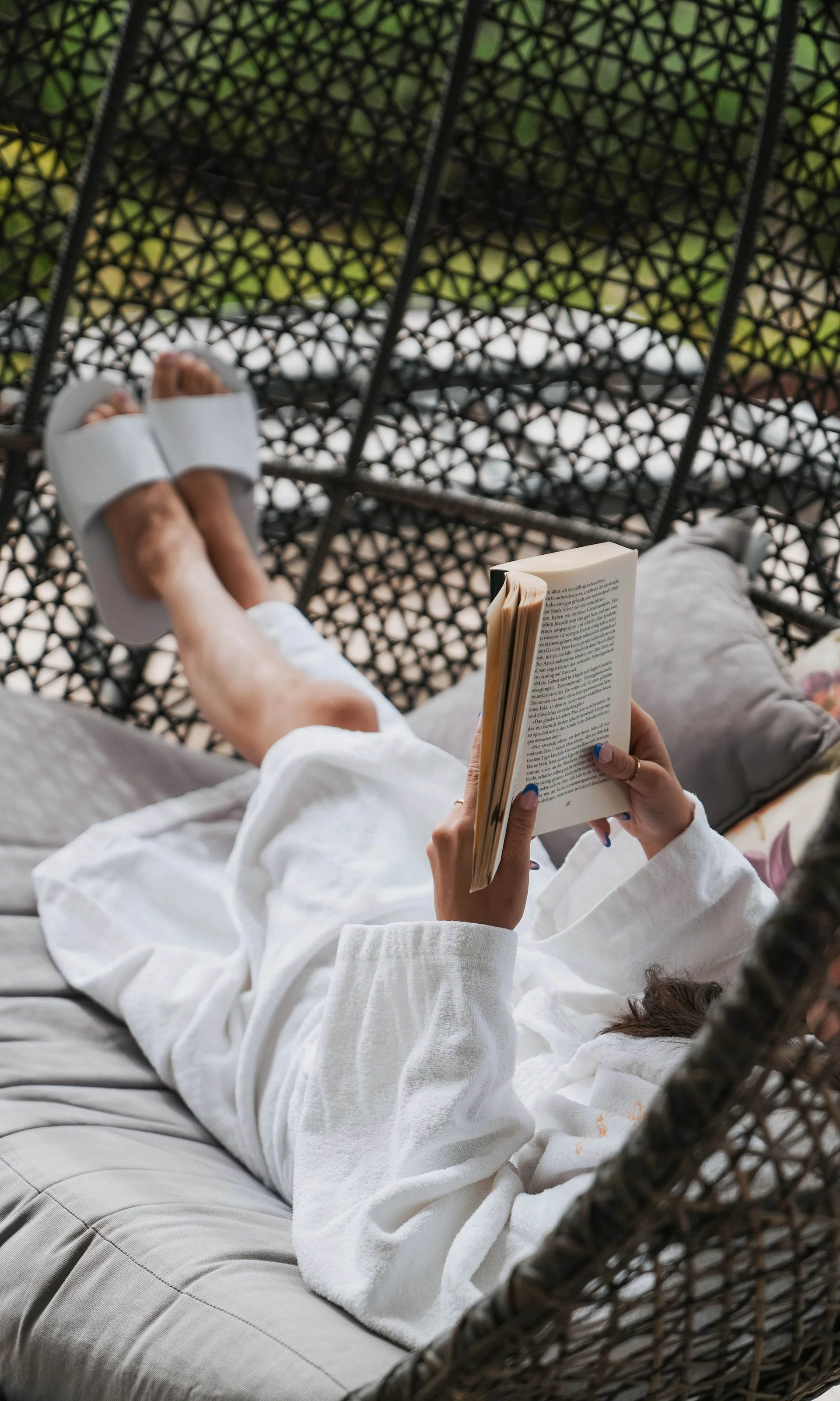 Euer Hotel in Schenna für Momente in #echtzeit Person in Bademantel entspannt auf Schaukelstuhl und liest Buch