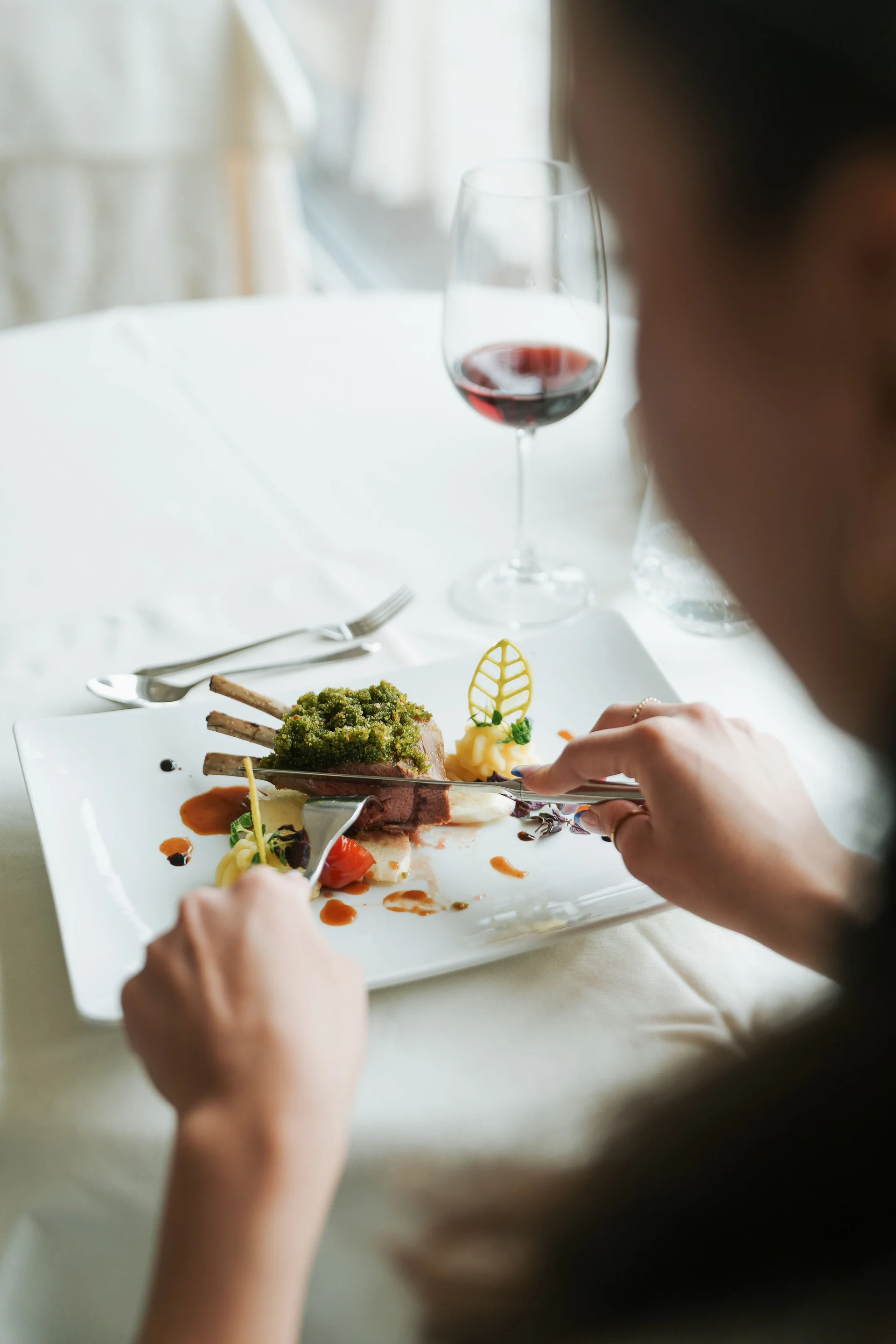 Euer Hotel in Schenna für Momente in #echtzeit Person isst Gerichte mit Lammkoteletts und rotem Wein im Restaurant