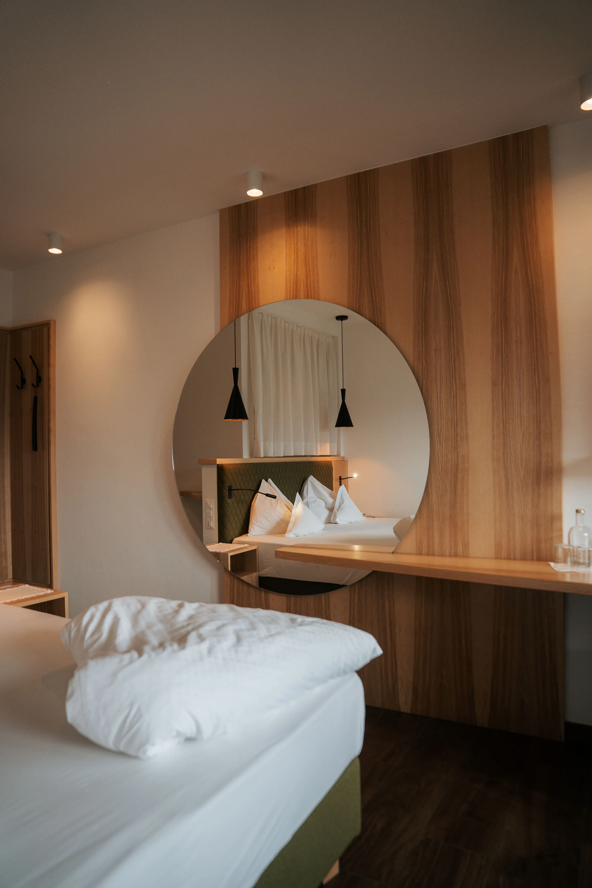 Euer Hotel in Schenna für Momente in #echtzeit Modernes Schlafzimmer mit rundem Spiegel und weißer Bettwäsche