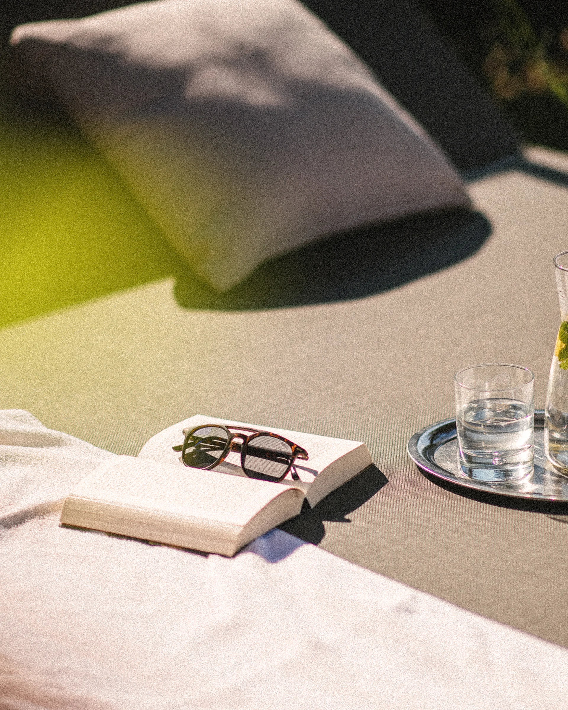 Euer Hotel in Schenna für Momente in #echtzeit Buch mit Sonnenbrille und Wasser mit Zitrone auf Liege draußen
