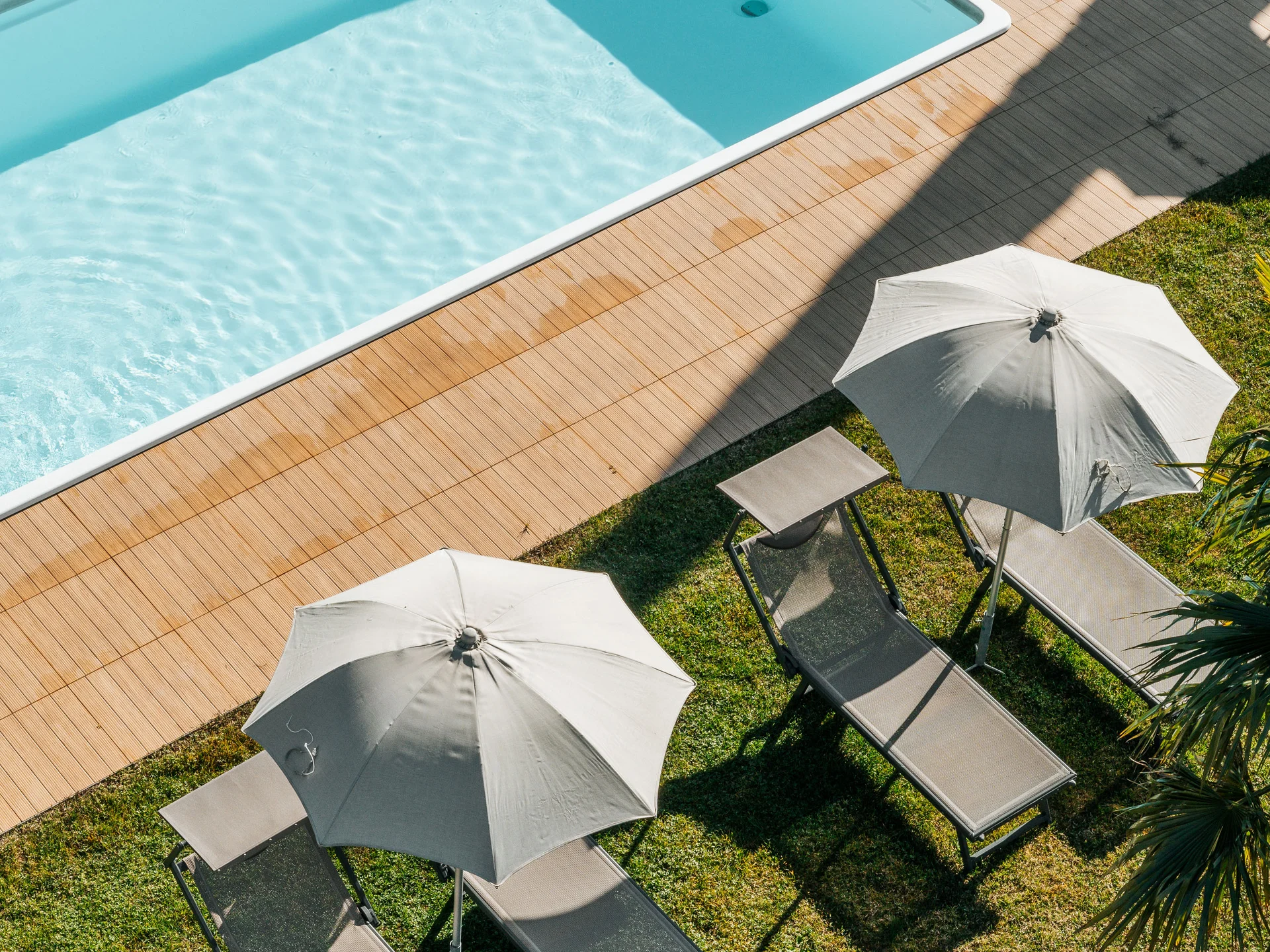 Euer Hotel in Schenna für Momente in #echtzeit Blick von oben auf Pool mit Liegestühlen und Sonnenschirmen im Garten